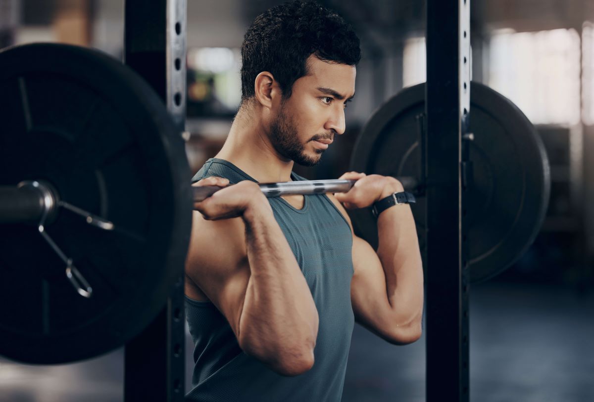 Man wearing a tank top in the gym performing front squat exercise