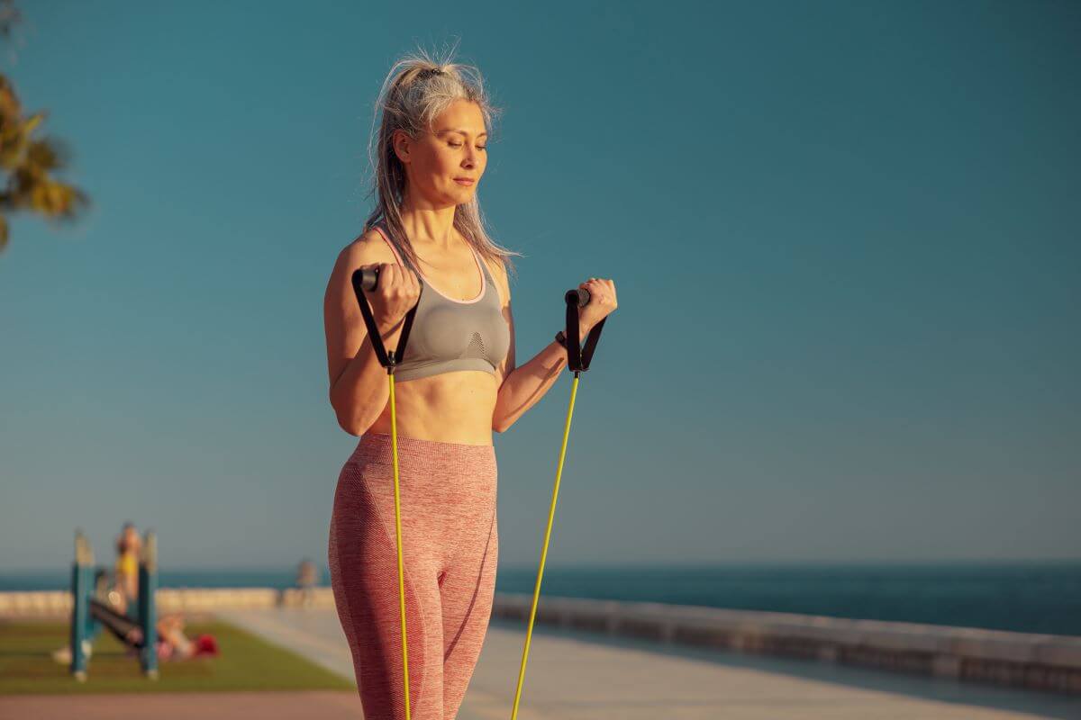 Woman performing Resistance Band Curls on beach