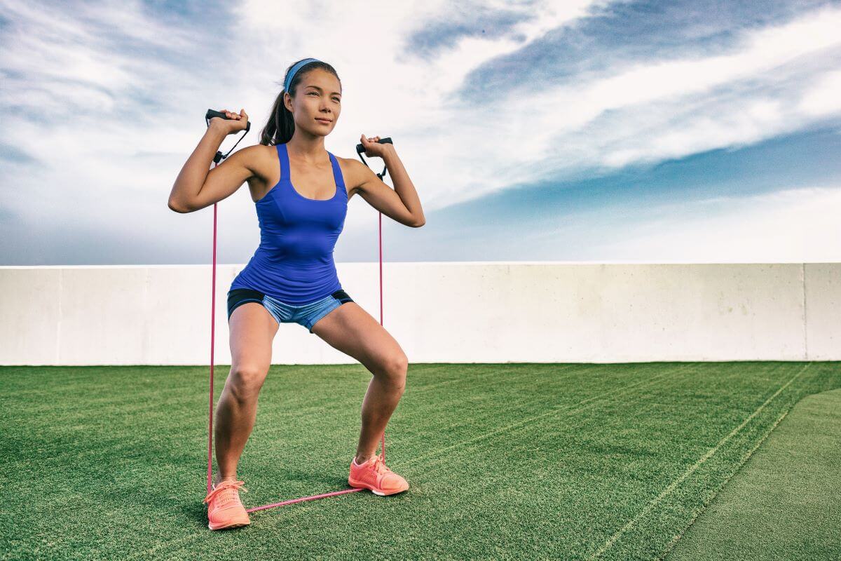 Woman performing resistance band squats outside