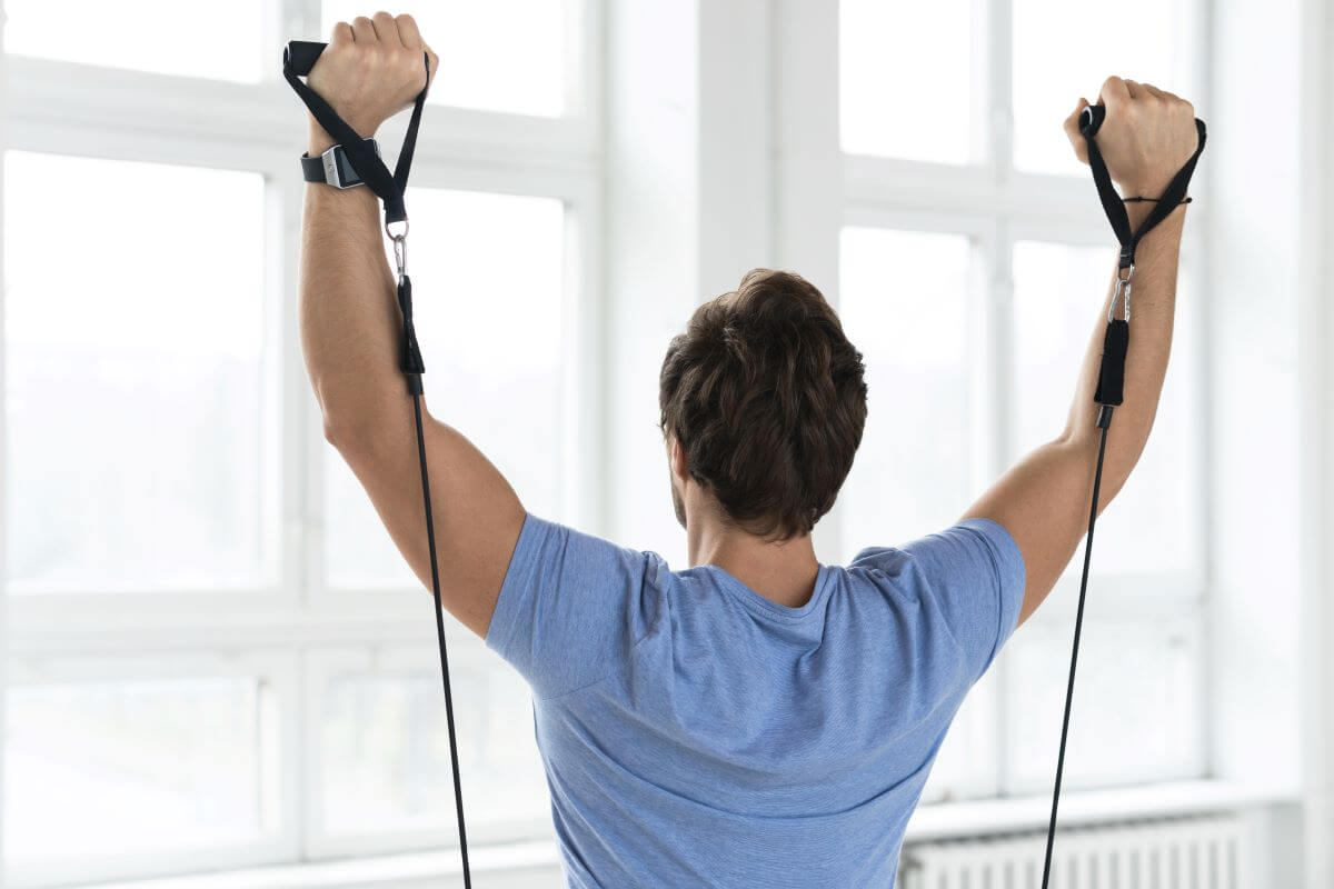 Man performing resistance band shoulder presses at home