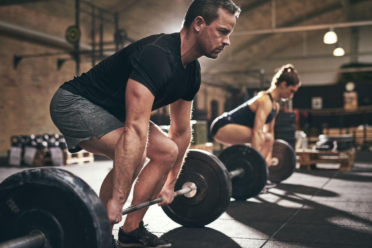 Man and Woman Performing Deadlifts to Build Trap Muscles