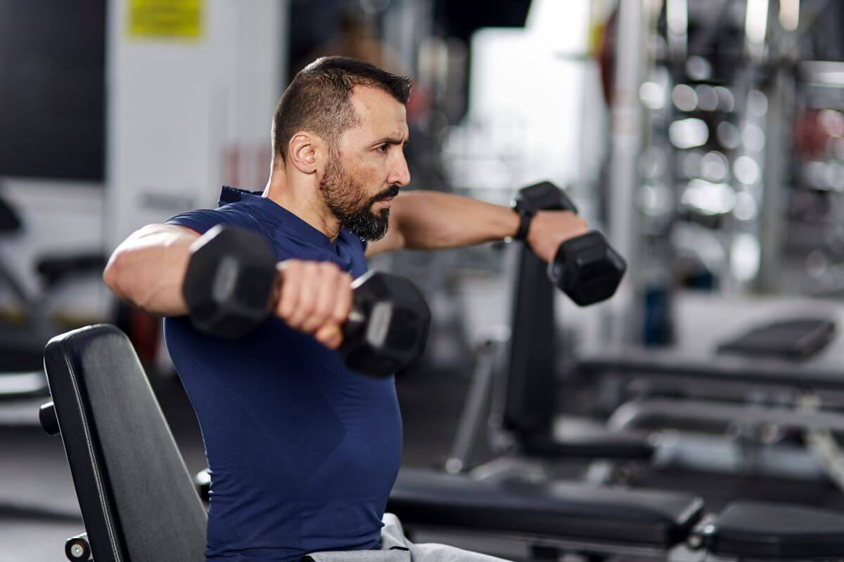 Man performing seated dumbbell lateral raises during workout