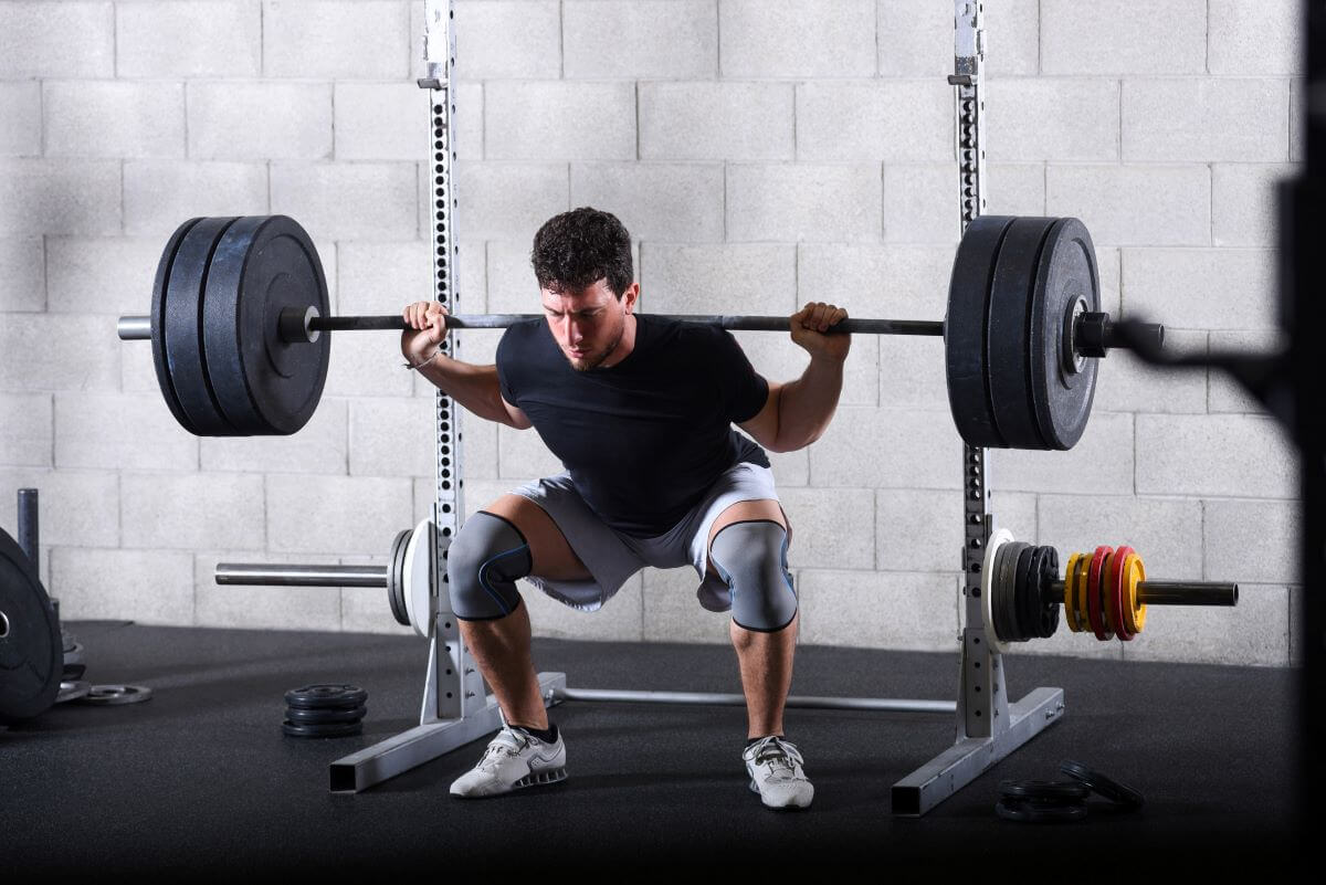 Athletic Man Performing Barbell Back Squats in tough full body superset article