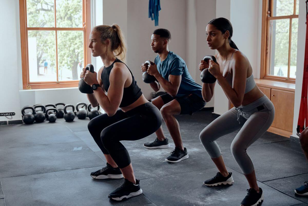 Men and women performing a kettlebell squat as part of a 2 day kettlebell workout