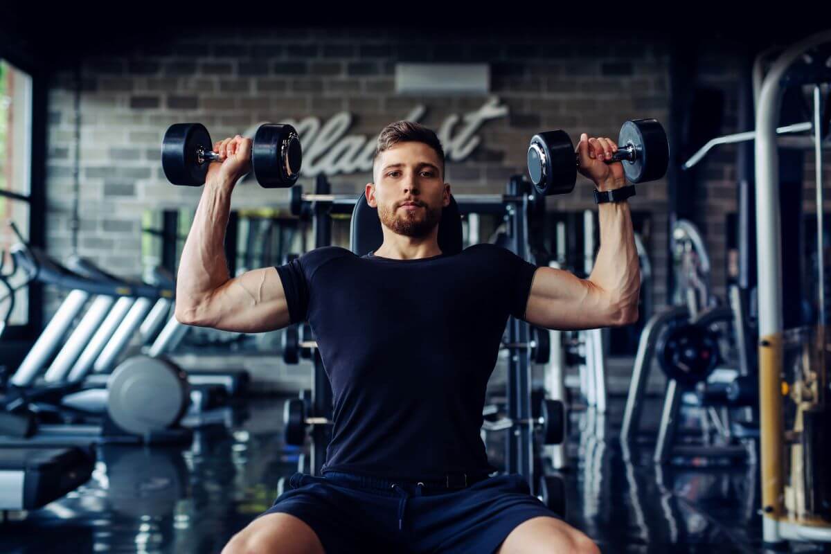 Man performing seated dumbbell shoulder press as part of a 2 day planet fitness workout