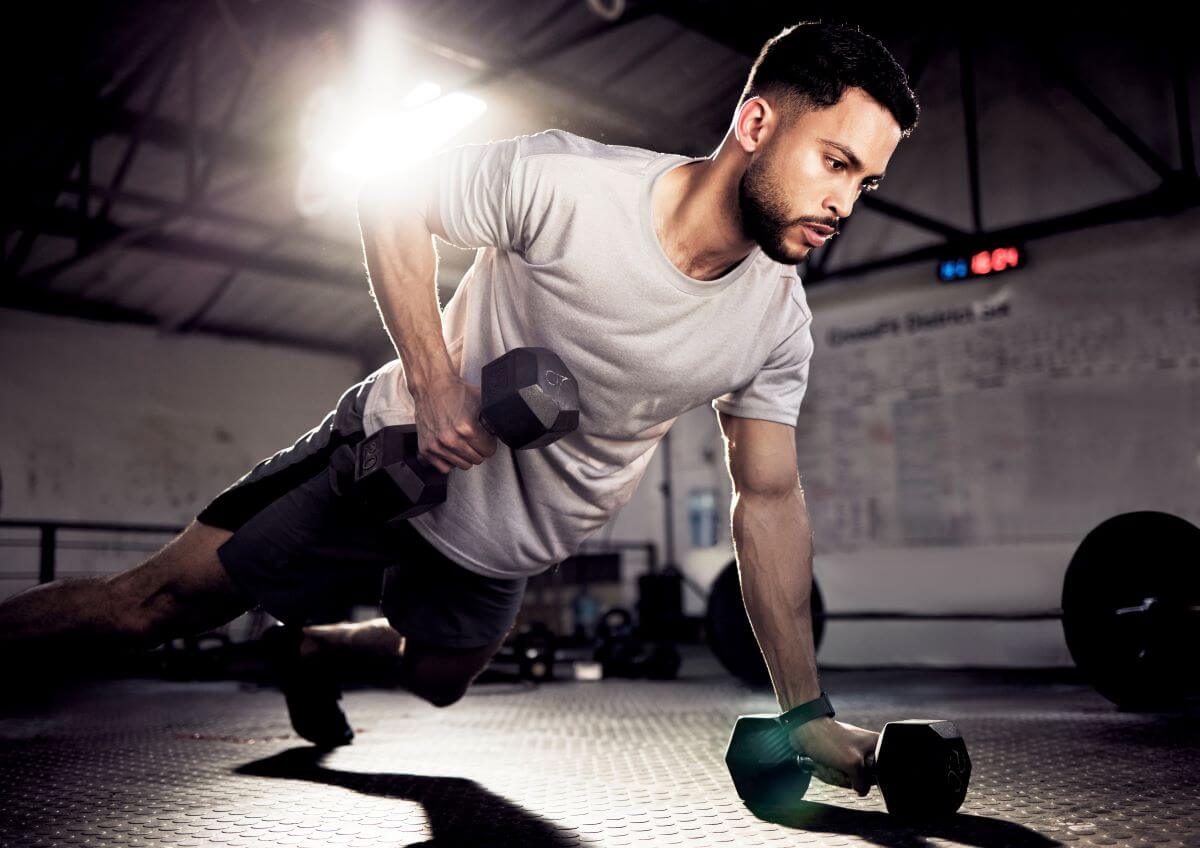 Man performing renegade rows as part of 6 day dumbbell workout routine