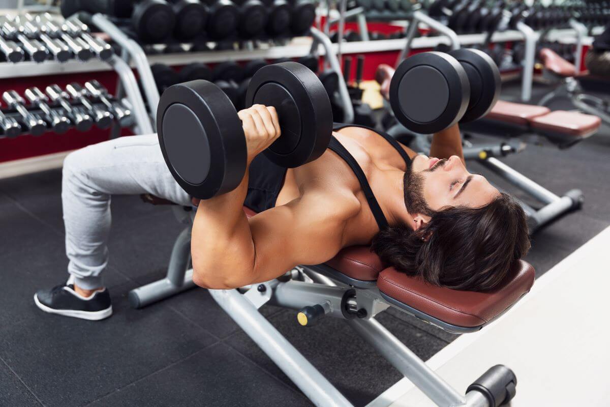 Man performing a dumbbell bench press as part of a dumbbell chest workout